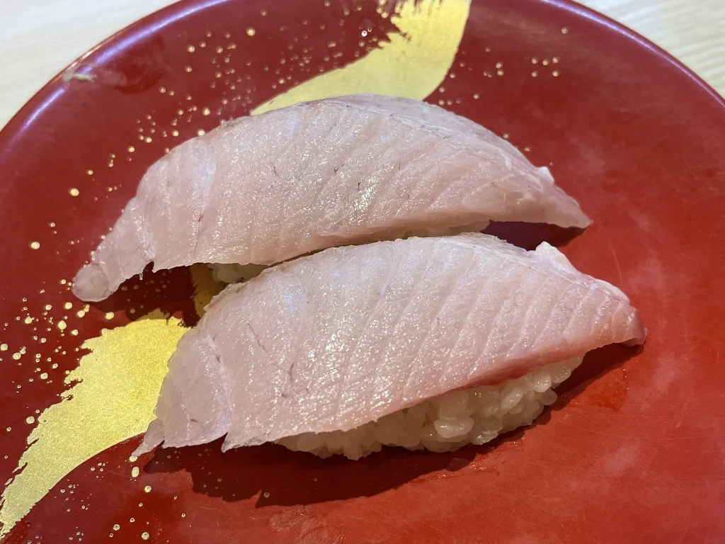 Winter Buri Nigiri Sushi Two pieces of fatty winter buri nigiri served on a red lacquer plate