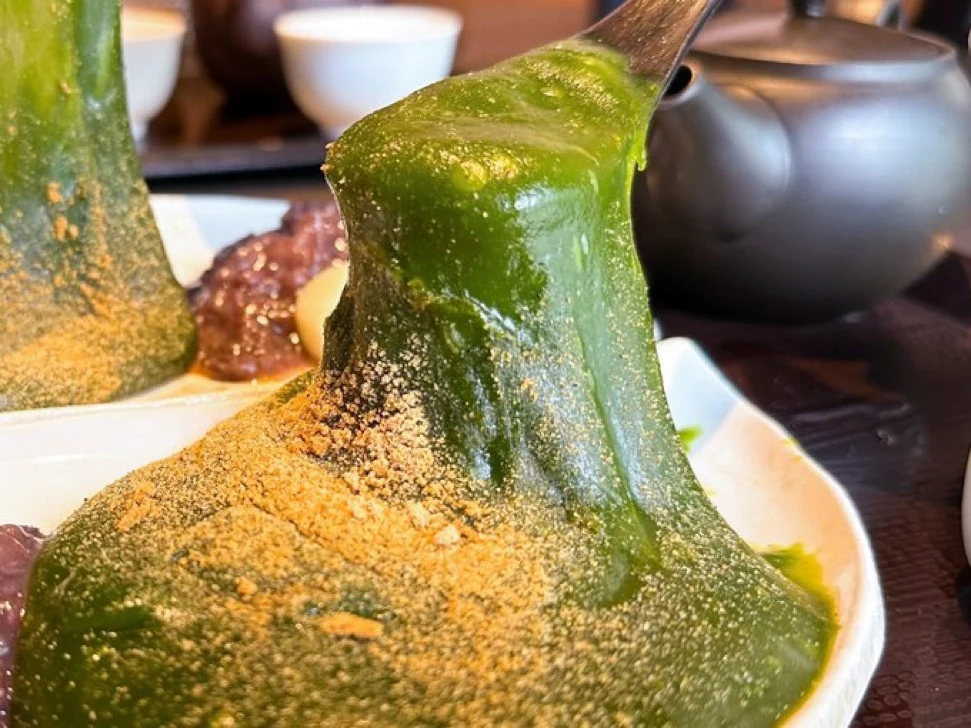 Matcha Kudzu Dessert with Kinako Matcha dessert lifting from a plate to show its elastic texture from added kudzu starch