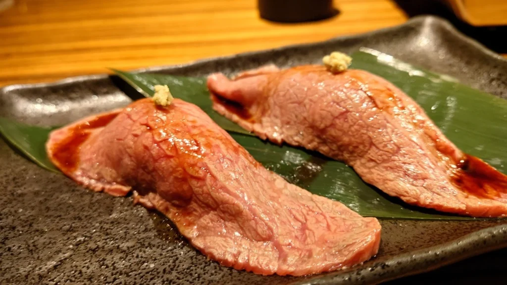 Seared A5 Wagyu Nigiri Sushi Two pieces of surface-seared A5 Wagyu nigiri served on a dark plate