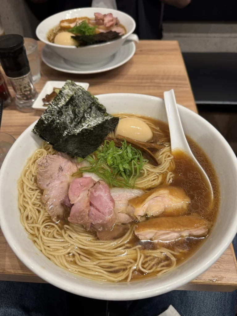 Bowl of shoyu ramen with assorted chashu, a seasoned egg, nori, bamboo shoots, and green onions
