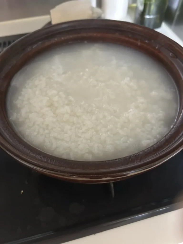 rice and cloudy cooking water actively steaming inside a brown donabe