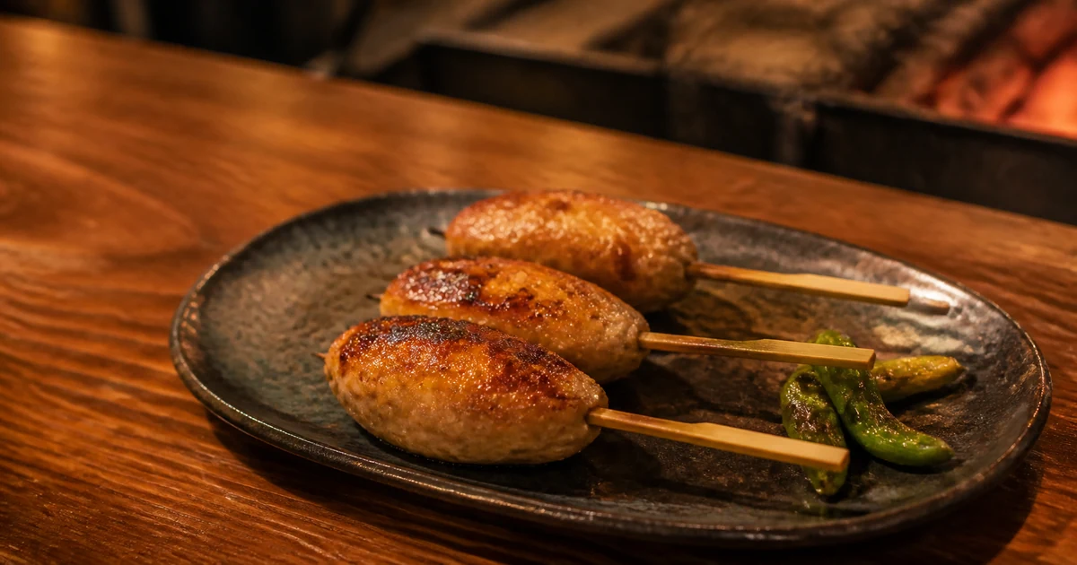 Grilled tsukune chicken meatball skewers on a ceramic plate