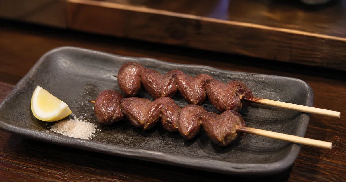 Two skewers of grilled chicken heart yakitori served with salt and lemon