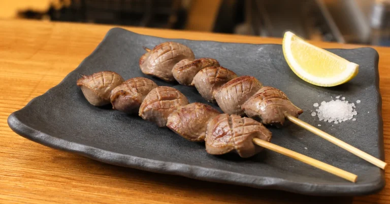 Two skewers of grilled chicken gizzard yakitori served with salt and lemon