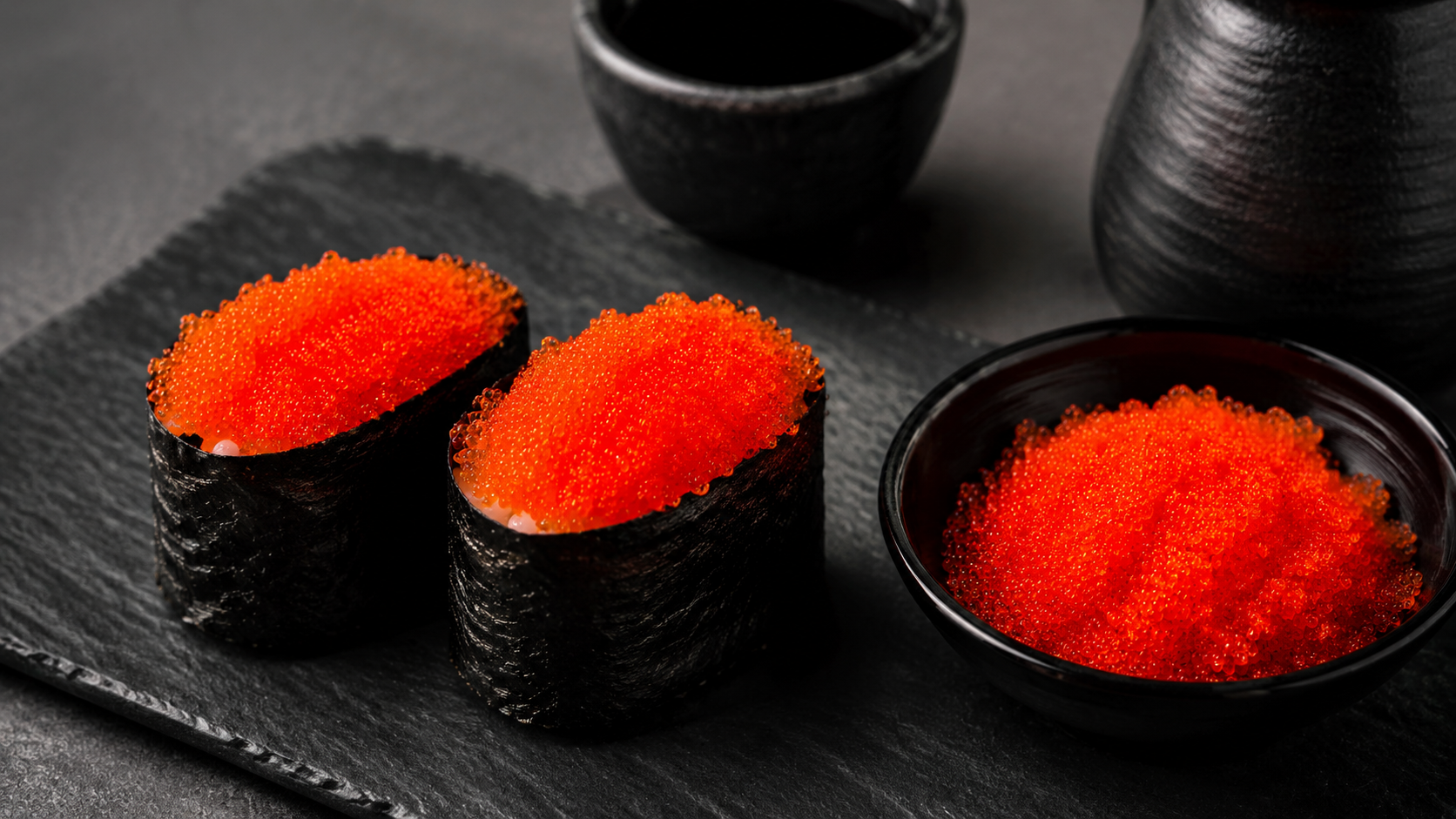 Tobiko flying fish roe served in two gunkan sushi pieces and a small black bowl