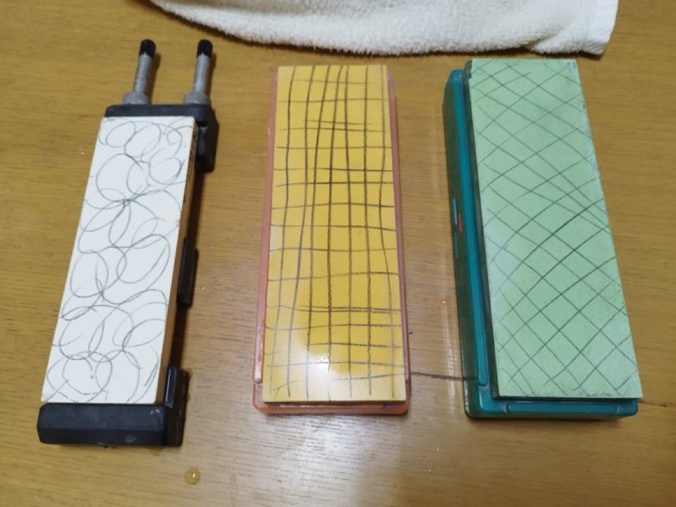 Pencil grid lines drawn across three Japanese whetstones before flattening