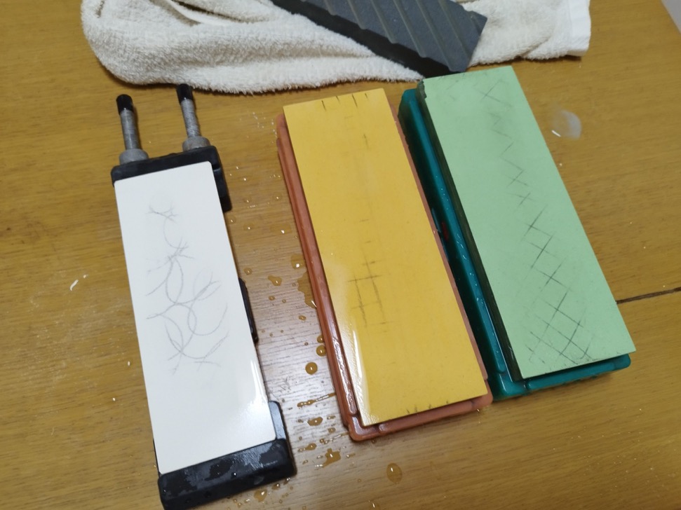 Partially removed pencil marks on three wet whetstones during flattening