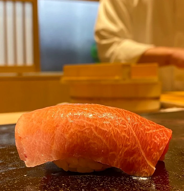 Marbled fatty tuna nigiri presented on a dark sushi plate