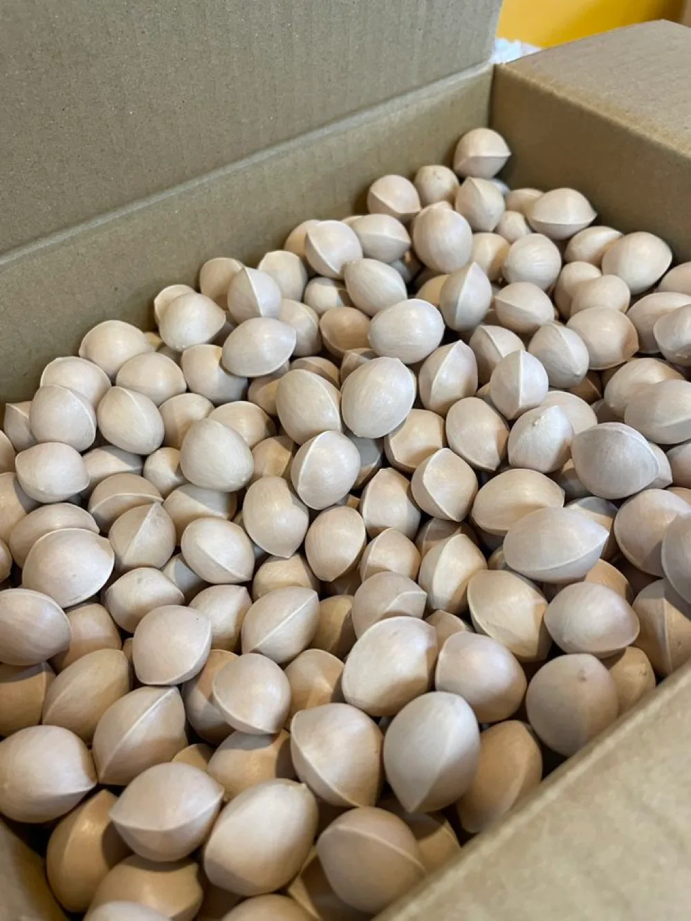 Pale hard shells of ginkgo nuts piled inside a cardboard box