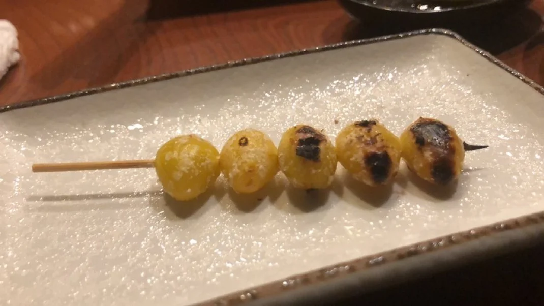 Five grilled ginkgo nuts arranged evenly on a bamboo skewer