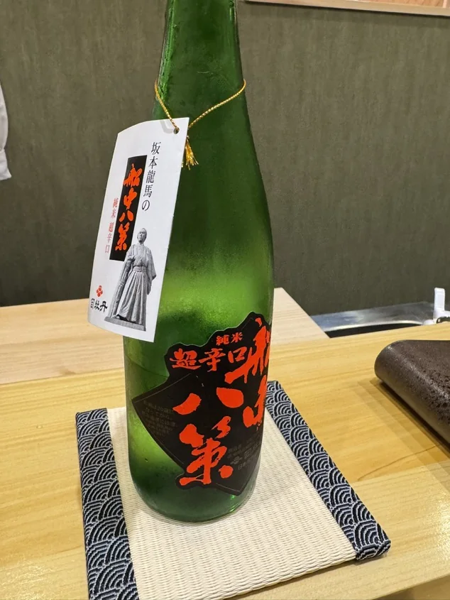 Sake bottle labeled Junmai and Super Dry in Japanese at a sushi counter