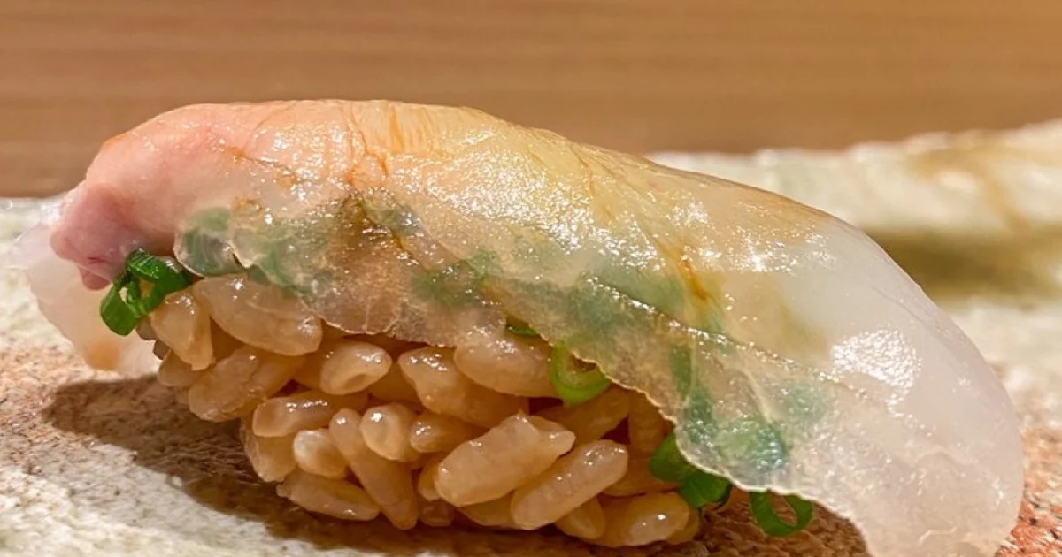 Kawahagi nigiri with thinly sliced white fish and green onion at a sushi counter