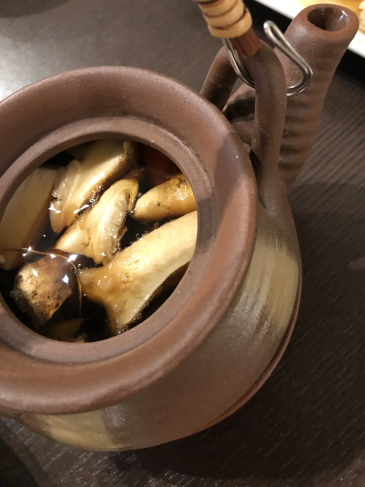 Matsutake slices in clear broth inside an open Japanese dobin teapot