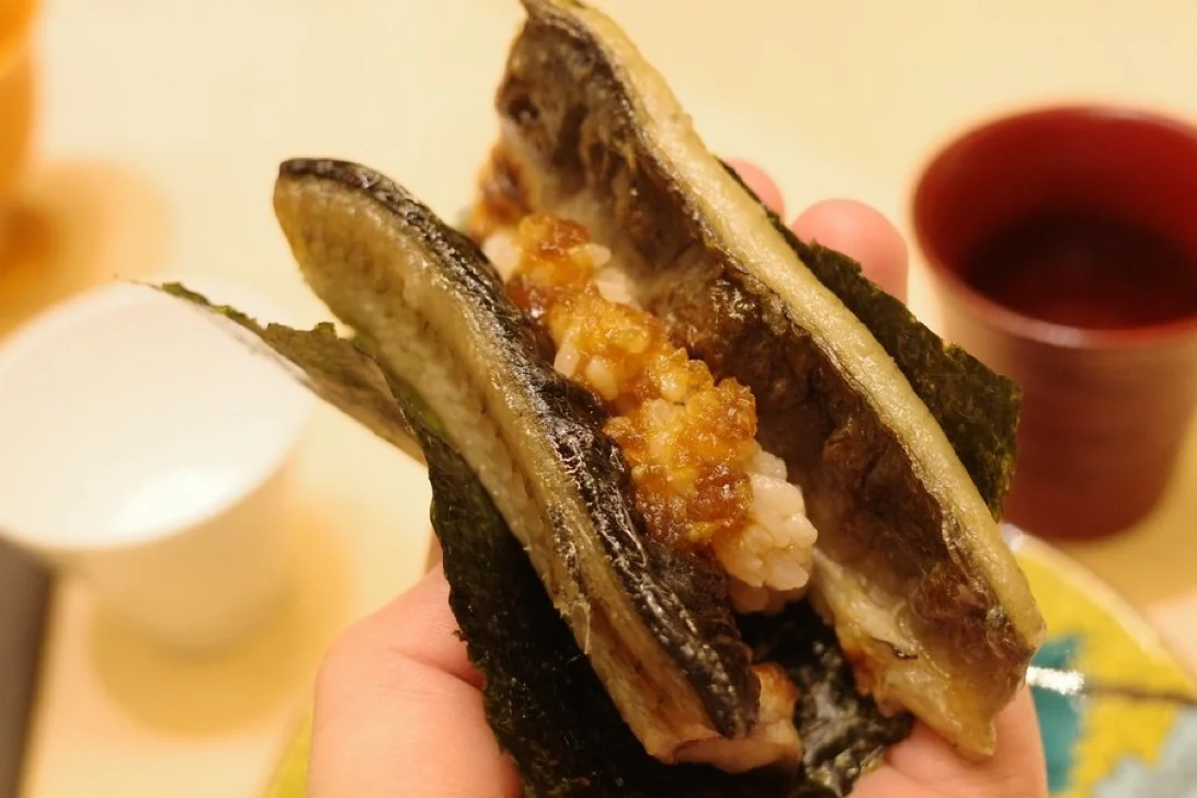 A piece of nori-wrapped sushi being held by hand