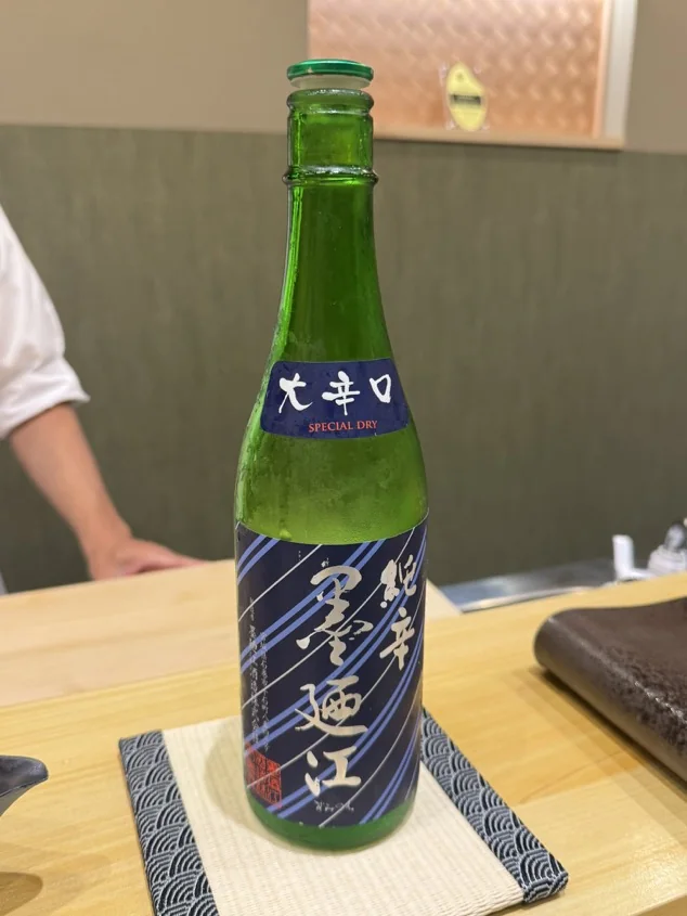 Green sake bottle with a neck label reading Special Dry at a sushi counter