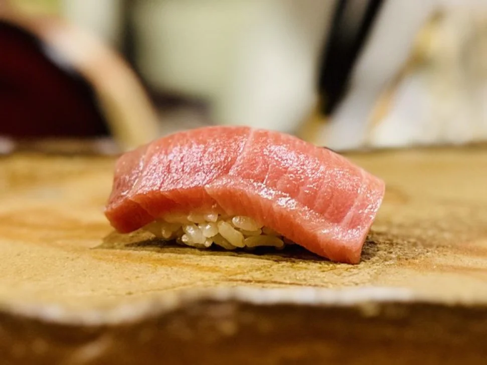 Tuna nigiri served on a ceramic plate at a Japanese sushi counter